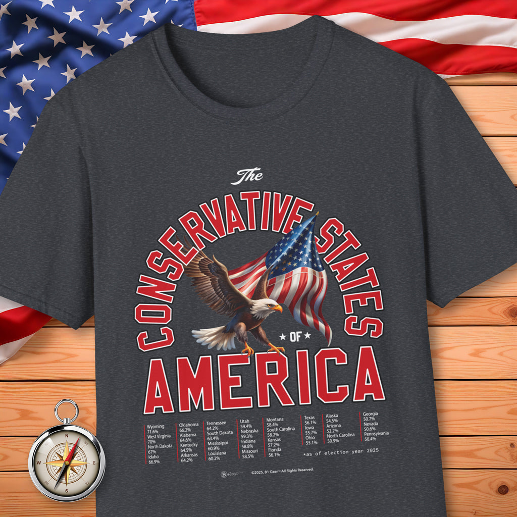 Dark gray t-shirt with 'The Conservative States of America' design featuring an eagle and American flag, placed on a wooden surface with an American flag in the background.